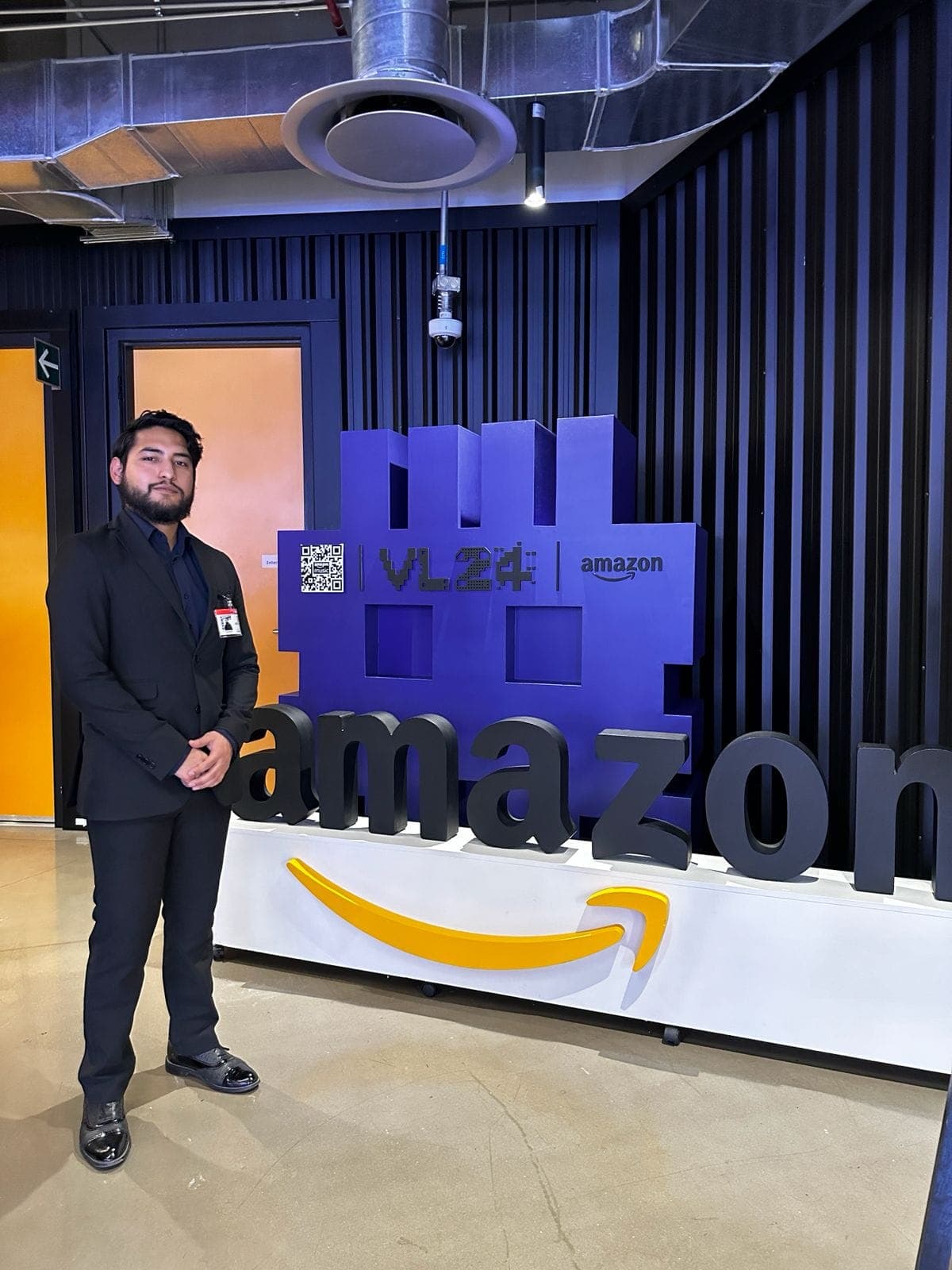 Ramses in a suit standing next to the giant Amazon logo at the VL24 event.