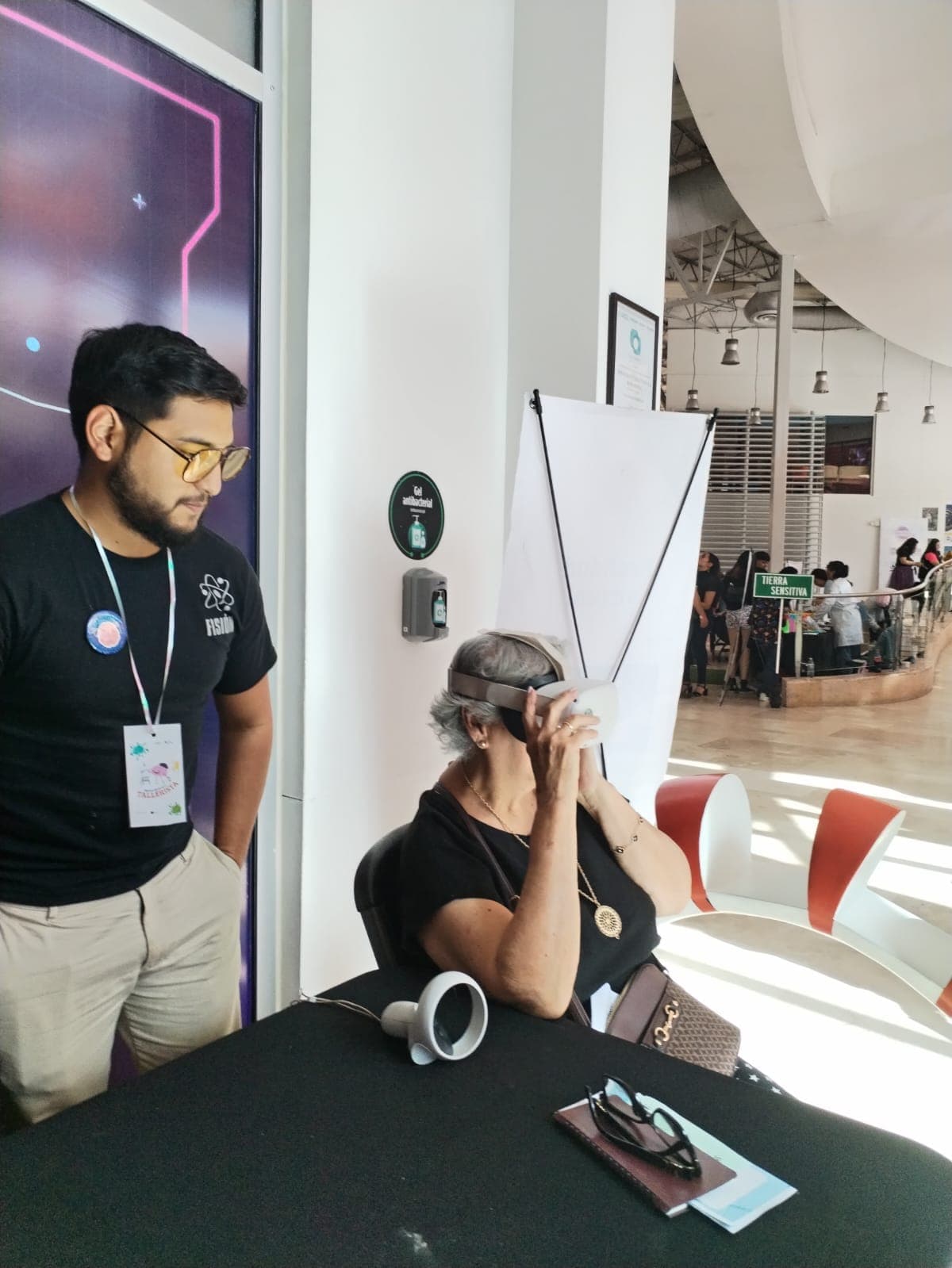 Ramses in a Fisión shirt guiding a participant using a VR headset at Talentosas.